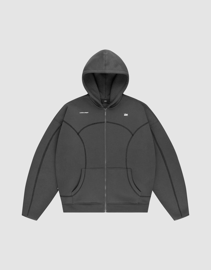 The LFDY Active Fleece Hooded Zip by LIVE FAST DIE YOUNG is a dark gray, oversized zip-up hoodie with a hood, subtle seam details, and a small white logo on the chest, shown against a plain light gray background. | plain