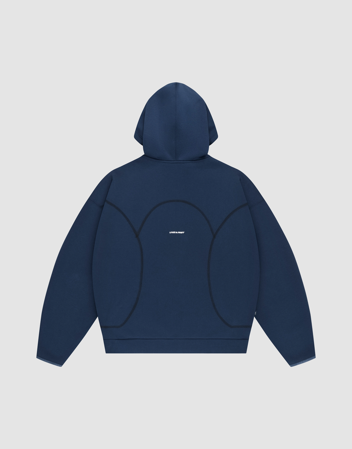 The LFDY Active Fleece Hooded Zip by LIVE FAST DIE YOUNG is shown laid flat, back facing up. This navy blue oversized hoodie features curved black seams, a small white logo at the center, and is set on a light gray background.