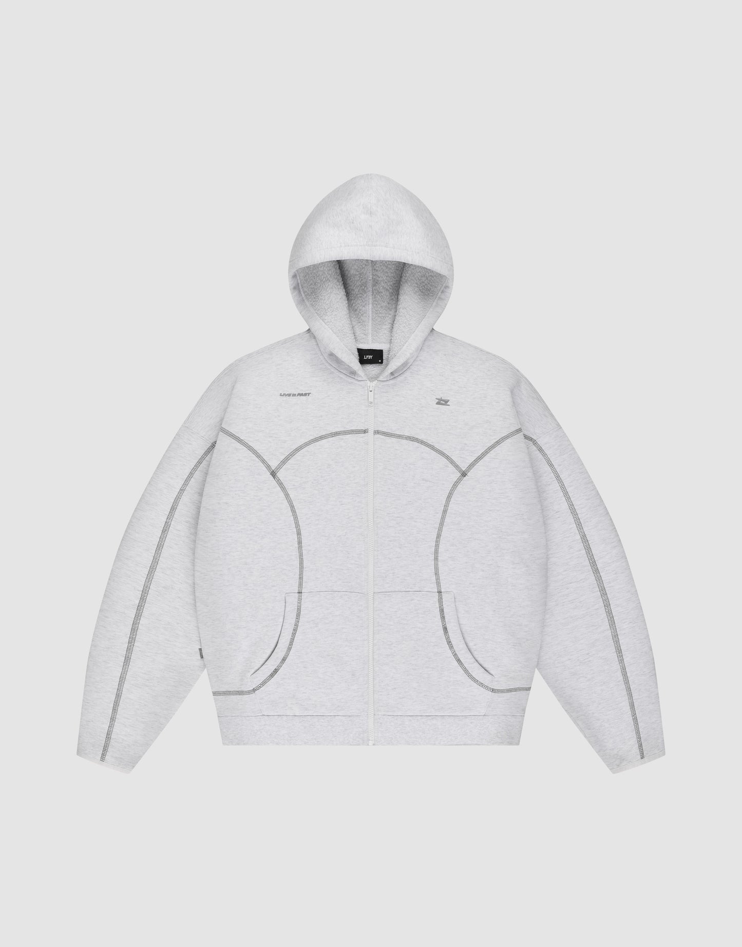 The LFDY Active Fleece Hooded Zip by LIVE FAST DIE YOUNG is a light gray oversized zip-up hoodie in 100% Baumwolle, featuring a hood, front pockets, and dark gray stitched seams outlining unique curved and straight patterns.
