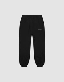 LFDY Trackpants by LIVE FAST DIE YOUNG: black regular-fit joggers with elastic waistband and cuffs, side pockets, and a small white logo on the upper left thigh, shown on a plain light grey background. | plain