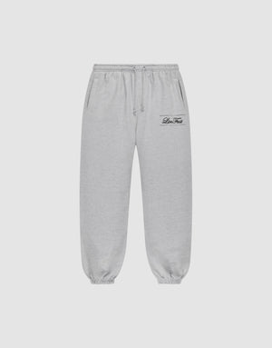 Light gray Wide Cuff Jogger sweatpants by LIVE FAST DIE YOUNG with a wide fit, elastic waistband with drawstring, side pockets, and elastic cuffs. Small black script logo on left thigh. Shown on a plain white background. | plain