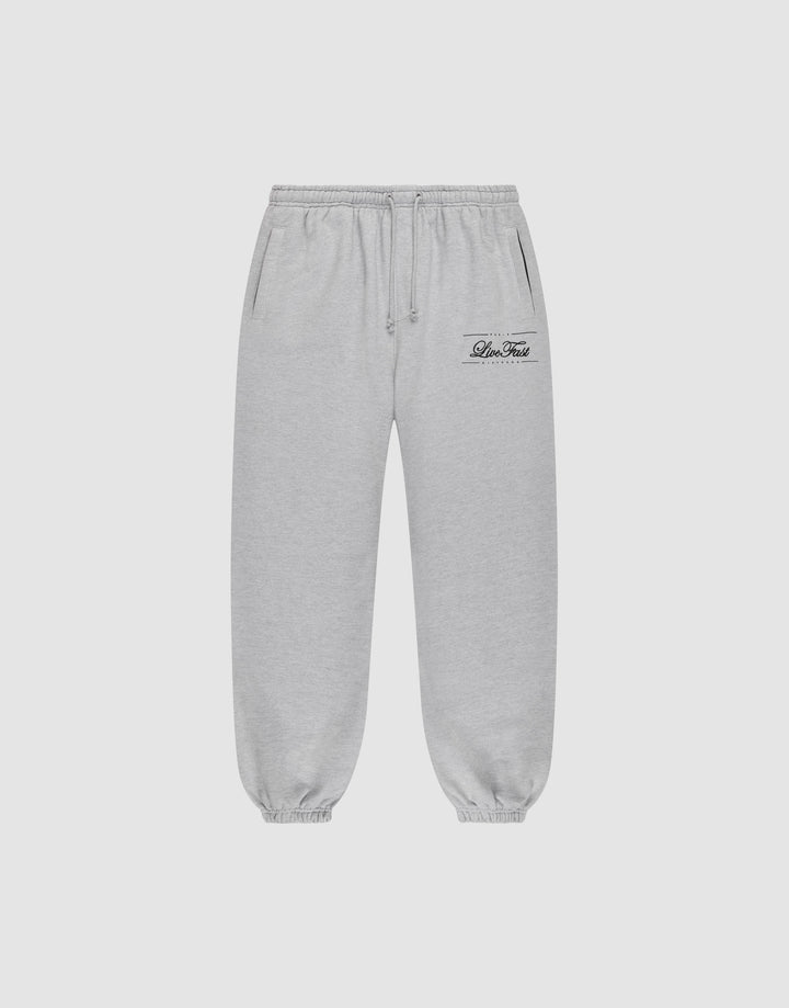 Light gray Wide Cuff Jogger sweatpants by LIVE FAST DIE YOUNG with a wide fit, elastic waistband with drawstring, side pockets, and elastic cuffs. Small black script logo on left thigh. Shown on a plain white background. | plain