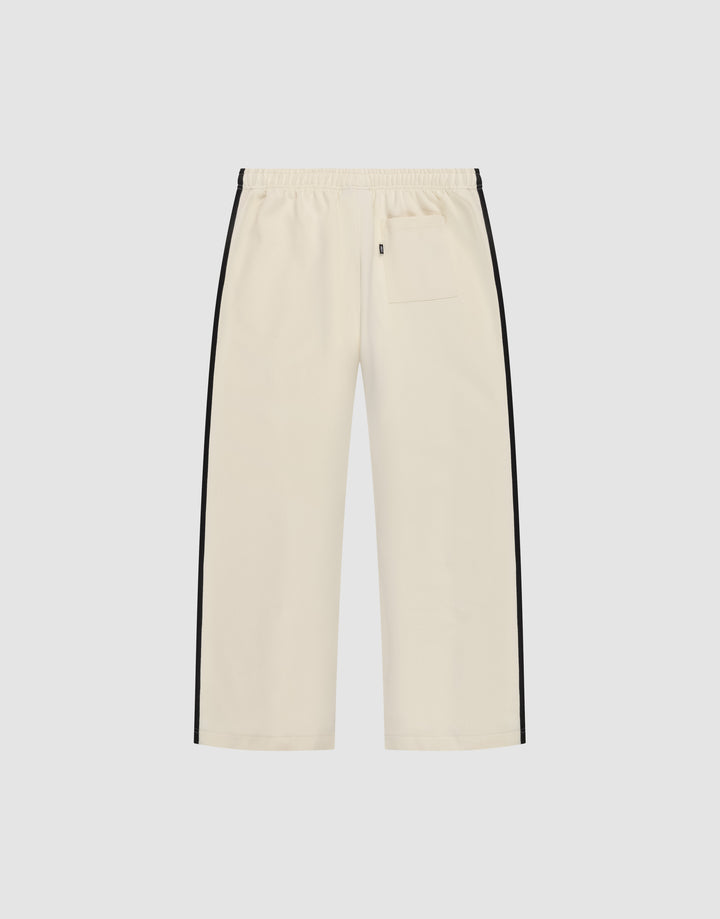The LFDY Striped Jogger by LIVE FAST DIE YOUNG features a cream color, wide fit, elastic waistband, black herringbone side stripes, and a single back pocket, shown against a plain white background.