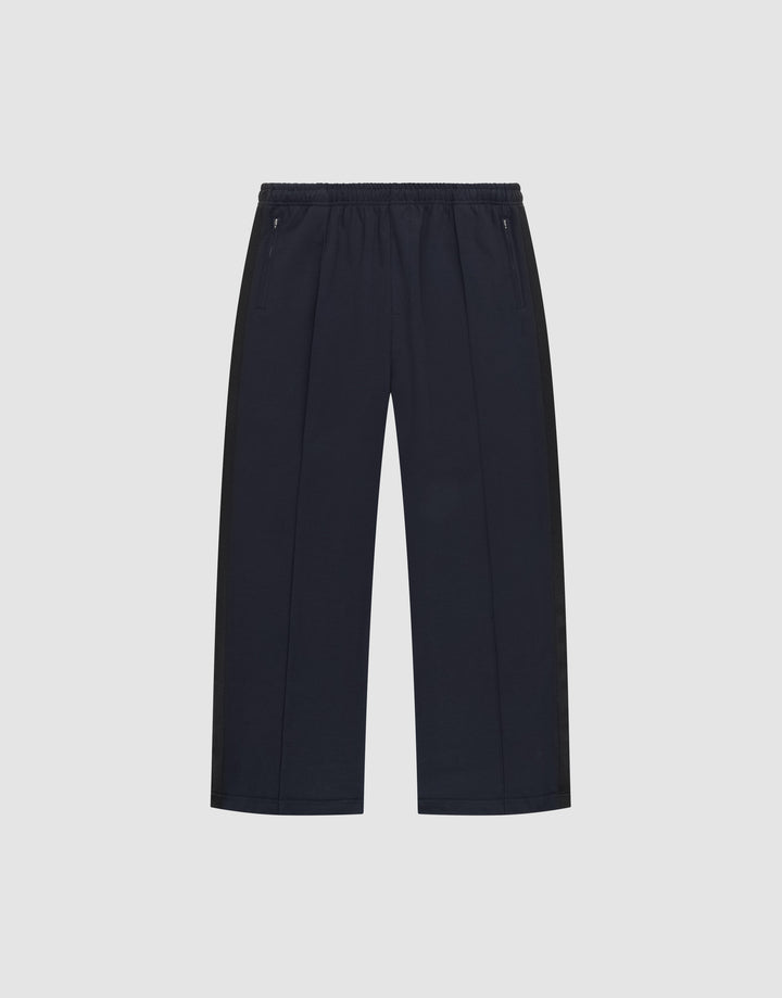 The LFDY Striped Jogger by LIVE FAST DIE YOUNG is a pair of black, wide-leg pants with an elastic waistband and zippered side pockets, featuring subtle Fischgräten-Tape accents, shown on a plain white background. | plain