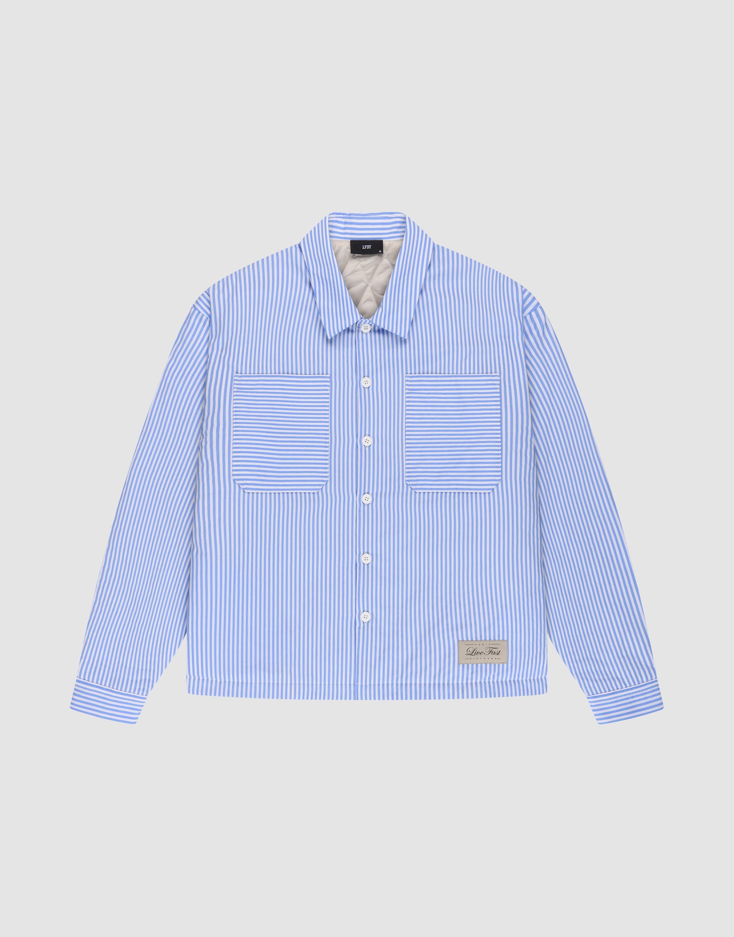 The LFDY Striped Padded Shirt by LIVE FAST DIE YOUNG features blue and white vertical stripes, an oversize fit, long sleeves, two front chest pockets, and a small rectangular label near the lower left hem. Displayed on a plain light background. | plain