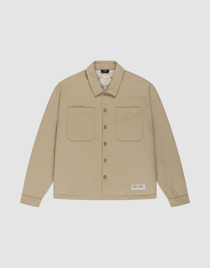 The LFDY Padded Shirt by LIVE FAST DIE YOUNG is a beige, padded overshirt with two front chest pockets, a collar, and a white label near the left hem, shown on a white background. | plain