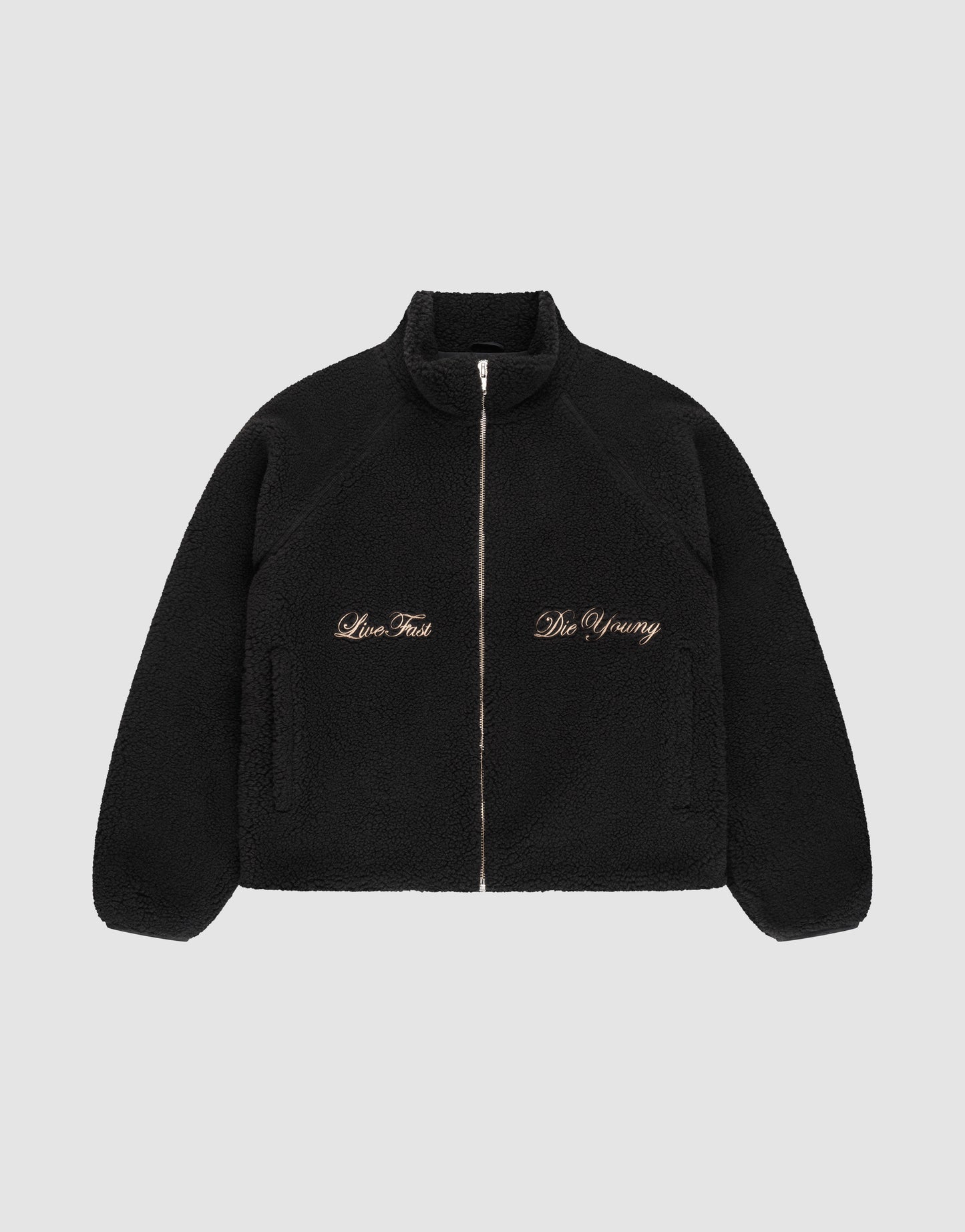 The LFDY Teddy Jacket by LIVE FAST DIE YOUNG is a black fleece jacket with raglan sleeves, side pockets, and gold "Live Fast" and "Die Young" embroidery on the chest, shown on a plain light gray background.
