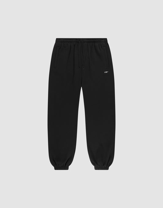The Basic Loose Jogger by LIVE FAST DIE YOUNG features an elastic waistband and cuffs, side pockets, a drawstring waist, and a small white logo on the left thigh, shown against a light gray background. | plain