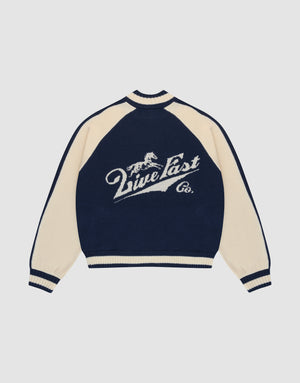 A navy blue and cream Boxy Knit Zip Jacket by LIVE FAST DIE YOUNG, with oversized fit, long raglan sleeves, and a large intarsia-knit running horse graphic above "Live Fast Co." script on the back. | plain