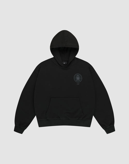 The LFDY Vandals Hooded by LIVE FAST DIE YOUNG is a black oversized hoodie featuring a small circular graphic and subtle text on the left chest, made from 100% Baumwolle, displayed on a light gray background.