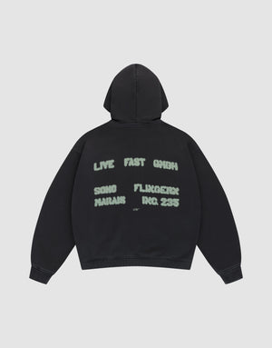 The Live Fast District Hooded Zip by LIVE FAST DIE YOUNG features an oversized black fit with light green spray-painted style text—LIVE FAST 6HIGH, SONG MARJAN, FLUXGEIST, INC. 235—and subtle LFDY branding on the back, shown flat on a plain light background. | plain