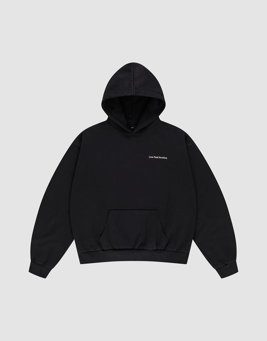 The LFDY Middlefinger Hooded by LIVE FAST DIE YOUNG is a plain black oversized pullover with a front pocket, small white "Live Fast Archive" text on the left chest, subtle front and back prints, shown on a light gray background.
