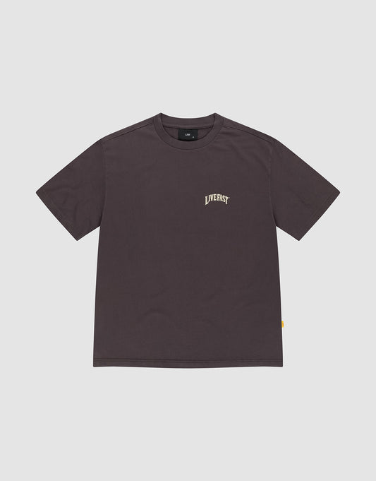 The LFDY x The Bulldog Tee by LIVE FAST DIE YOUNG is a plain dark brown oversized short-sleeve shirt made from 100% Baumwolle, featuring "LIVEFAST" in small, light letters on the left chest, shown on a light gray background.