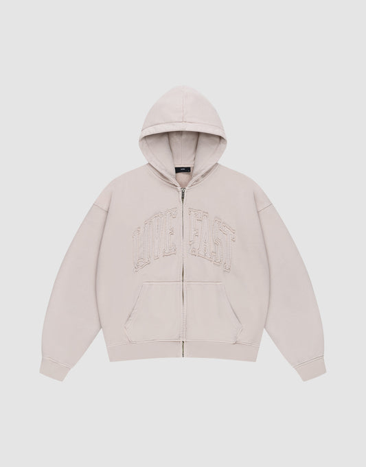The Ripped College Hooded Zip by LIVE FAST DIE YOUNG is a beige oversized zip-up hoodie with a hood, front pockets, and large distressed "LIVE FAST" embroidery on the chest, shown against a plain white background.