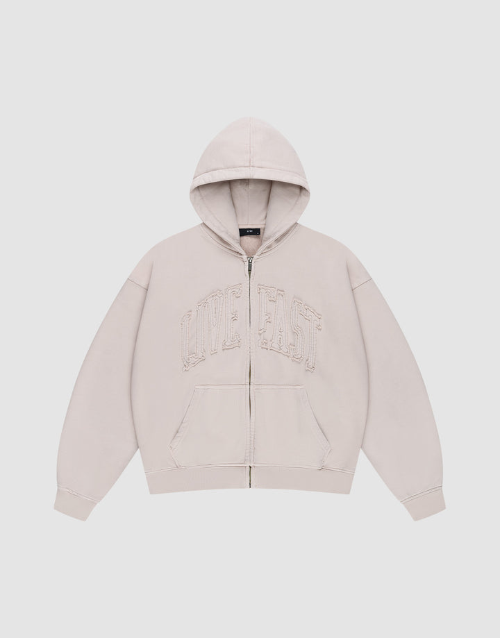 The Ripped College Hooded Zip by LIVE FAST DIE YOUNG is a beige oversized zip-up hoodie with a hood, front pockets, and large distressed "LIVE FAST" embroidery on the chest, shown against a plain white background.| plain