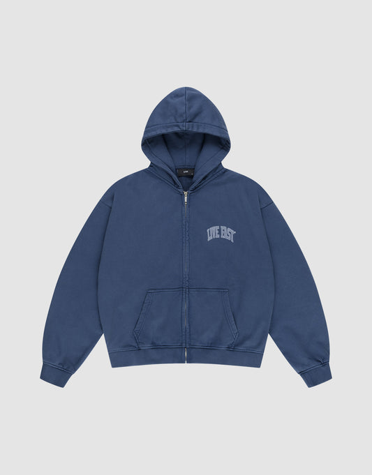 The Live Fast Berlin Hooded Zip by LIVE FAST DIE YOUNG is a blue, oversized zip-up hoodie with a hood, front pockets, and "LIVE FAST" in small white print on the left chest, made from 100% Baumwolle and shown on a plain light background.