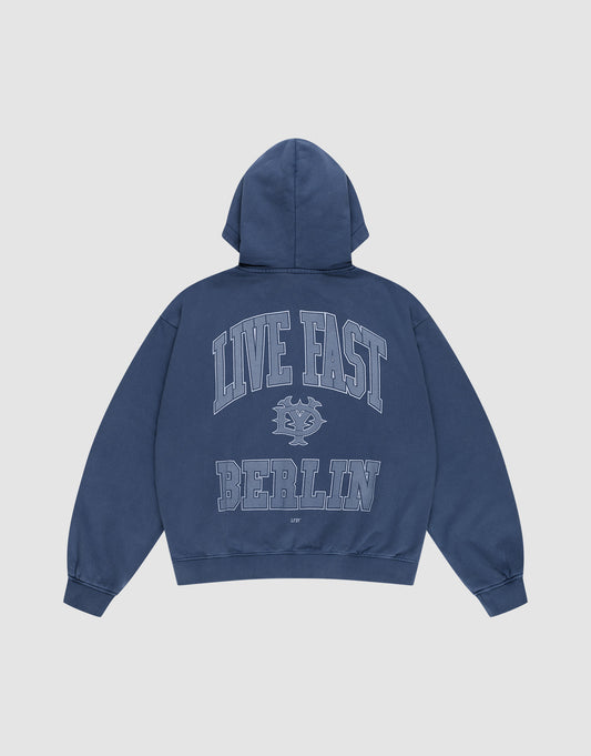 The LIVE FAST DIE YOUNG Live Fast Berlin Hooded Zip is an oversize fit blue sweatshirt with a hood, featuring "LIVE FAST" in large letters, a small graphic below, and bold "BERLIN" on the back. Made from 100% Baumwolle with a vintage wash. Shown on white background. | plain