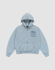 The LFDY 55 Hooded Zip by LIVE FAST DIE YOUNG is a light blue, oversized zip-up hoodie with a front pocket, hood, and dark blue LIVE FAST graphic with laurel wreath on the left chest. Made from 100% Baumwolle. Shown laid flat on a white background. | plain