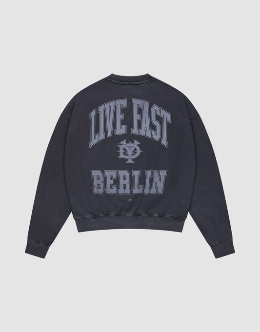 The Live Fast Berlin Sweater by LIVE FAST DIE YOUNG is an oversized dark navy sweatshirt made from 100% cotton, with large light blue "LIVE FAST" and "BERLIN" text plus a stylized logo on the back. | plain