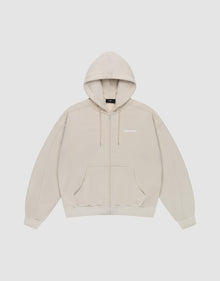 The LFDY Pleated Hooded Zip by LIVE FAST DIE YOUNG is a light beige oversized zip-up hoodie with a drawstring hood, front pockets, and small white logo on the chest. Made from 100% cotton and shown against a plain white background. | plain