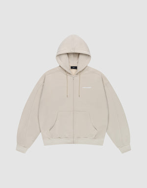 The LFDY Pleated Hooded Zip by LIVE FAST DIE YOUNG is a light beige oversized zip-up hoodie with a drawstring hood, front pockets, and small white logo on the chest. Made from 100% cotton and shown against a plain white background. | plain