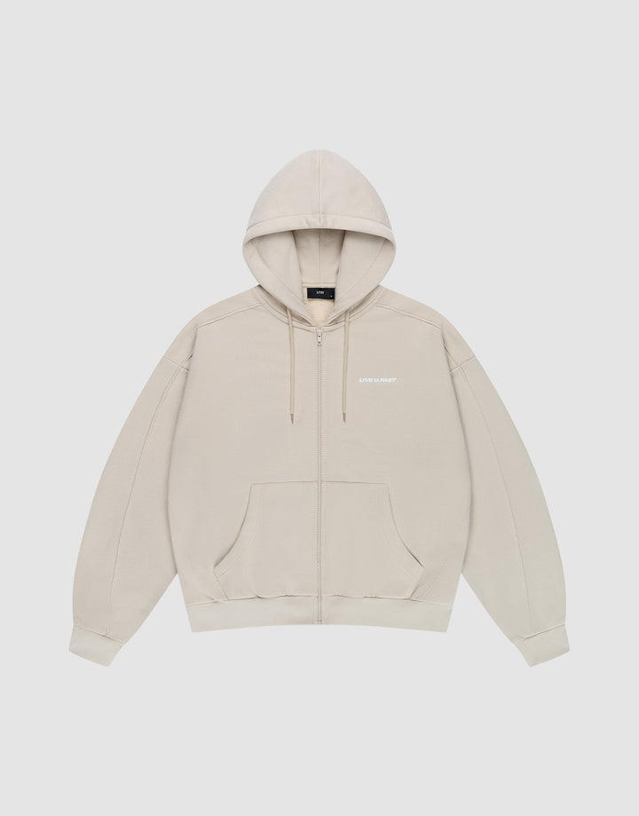 The LFDY Pleated Hooded Zip by LIVE FAST DIE YOUNG is a light beige oversized zip-up hoodie with a drawstring hood, front pockets, and small white logo on the chest. Made from 100% cotton and shown against a plain white background. | plain