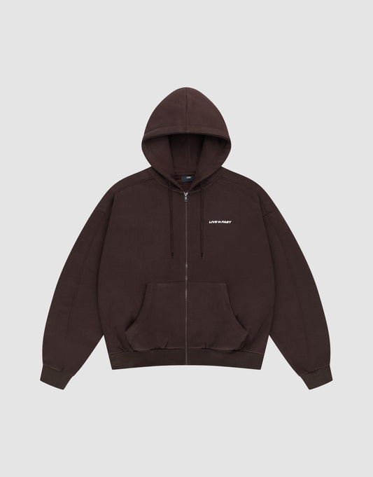 The LFDY Pleated Hooded Zip by LIVE FAST DIE YOUNG is a dark brown oversized zip-up hoodie with a drawstring hood, front pockets, and small white LIFE FAST text on the chest. Made from 100% Baumwolle. Shown on a plain light gray background. | plain