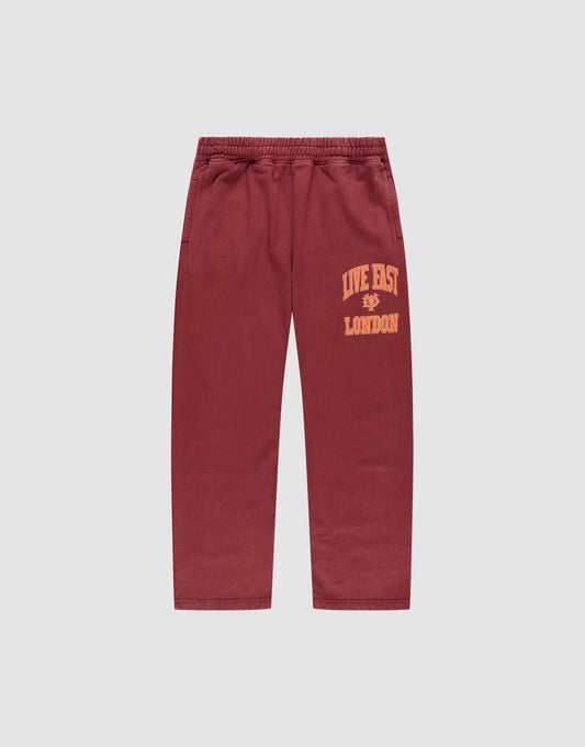 The LIVE FAST DIE YOUNG Live Fast London Wide Jogger in maroon, made from cotton, features a wide elastic waistband, side pockets, and "LIVE FAST LONDON" in yellow on the left thigh. Pants shown laid flat on a light gray background. | plain