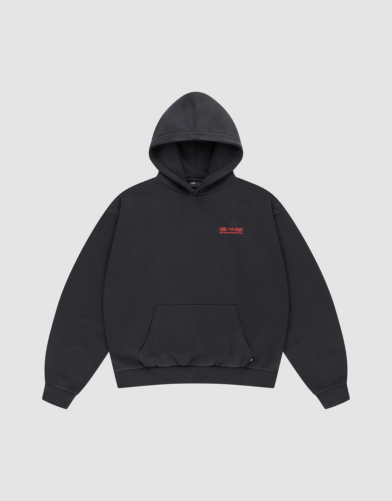 The LIVE FAST DIE YOUNG Hit and Run Hooded is a plain black oversized sweatshirt with a front pouch pocket and small red text discharge print on the left chest, shown on a light gray background.