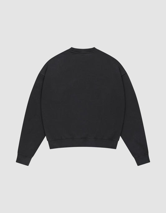 The LIVE FAST DIE YOUNG Live – Fast Sweater is shown flat from the back on a light grey background. This black Baumwolle pullover has an oversize fit, long sleeves, and ribbed cuffs and hem.