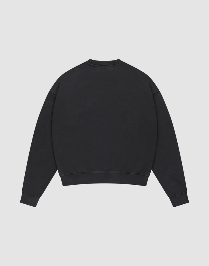The LIVE FAST DIE YOUNG Live – Fast Sweater is shown flat from the back on a light grey background. This black Baumwolle pullover has an oversize fit, long sleeves, and ribbed cuffs and hem.