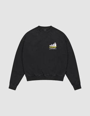 The LFDY Supply Sweater by LIVE FAST DIE YOUNG is a black oversized crewneck with a small colorful graphic and “LIVEST at the university” text on the left chest, crafted from a soft cotton-polyester blend and shown on a light grey background. | plain