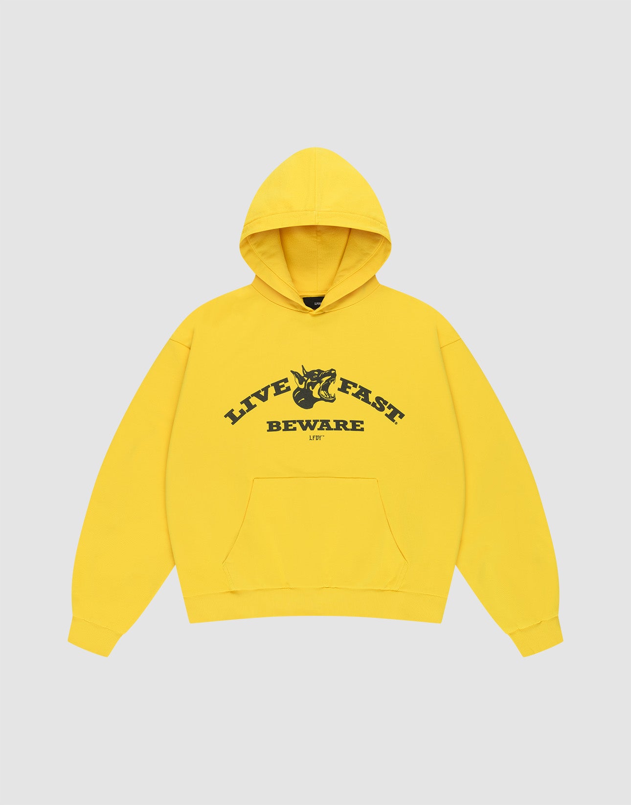 The Live Fast Beware Hooded by LIVE FAST DIE YOUNG is an oversize yellow hoodie made of 100% Baumwolle, featuring black "LIVE FAST. BEWARE" text and a horned skull illustration on the chest, set against a light gray background.