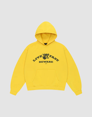 The Live Fast Beware Hooded by LIVE FAST DIE YOUNG is an oversize yellow hoodie made of 100% Baumwolle, featuring black "LIVE FAST. BEWARE" text and a horned skull illustration on the chest, set against a light gray background.| plain