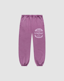 Die Loyal Loose Jogger von LIVE FAST DIE YOUNG sind lila Jogginghosen aus Baumwolle mit elastischem Bund und Bündchen, Vintage-Waschung und weißem LIVE FAST-Print am Oberschenkel, präsentiert vor grauem Hintergrund. | plain