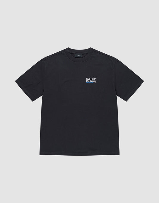 The Live Fast NY Tee by LIVE FAST DIE YOUNG is an oversized black cotton short-sleeve t-shirt with “Live Fast* Die Young” in white on the left chest, shown against a light gray background.