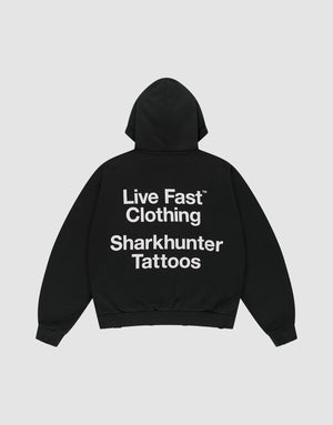 The LFDY Sharkhunter Hooded by LIVE FAST DIE YOUNG is a black oversized cotton hoodie with the hood up, shown flat on a light background. A large white back print reads: Live Fast Clothing Sharkhunter Tattoos. | plain