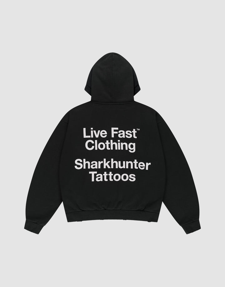 The LFDY Sharkhunter Hooded by LIVE FAST DIE YOUNG is a black oversized cotton hoodie with the hood up, shown flat on a light background. A large white back print reads: Live Fast Clothing Sharkhunter Tattoos.