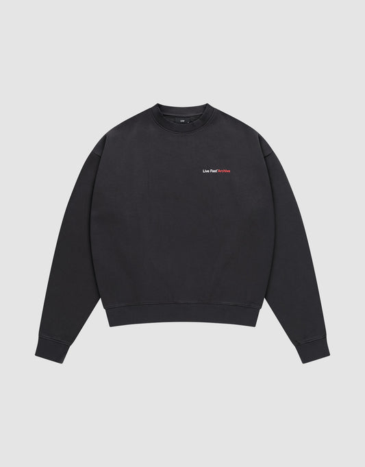 The LFDY F*ck Sweater by LIVE FAST DIE YOUNG is a black oversized crewneck with long sleeves, ribbed cuffs and hem, and small red “Live Fast Die Rich” text on the chest. Made from a cotton-polyester blend. Shown laid flat on a white background.