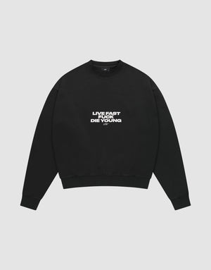The Fuck Die Young Sweater by LIVE FAST DIE YOUNG is a black oversized crewneck in a soft cotton-poly blend, with white "LIVE FAST LIVE YOUNG DIE YOUNG" text on the chest, shown laid flat on a light gray background. | plain