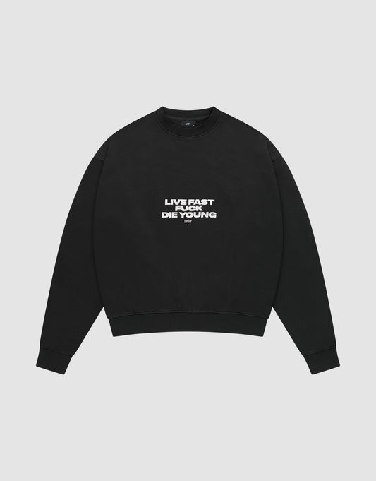 The Fuck Die Young Sweater by LIVE FAST DIE YOUNG is a black oversized crewneck in a soft cotton-poly blend, with white "LIVE FAST LIVE YOUNG DIE YOUNG" text on the chest, shown laid flat on a light gray background. | plain