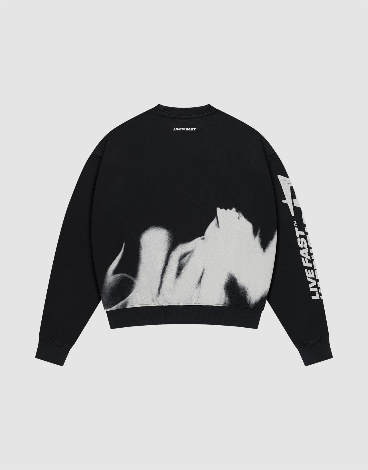 The LFDY Mystic Sweater by LIVE FAST DIE YOUNG is a black, oversized 100% cotton sweatshirt with white flame designs on the lower back and "LIVE FAST" printed on the front and back, shown against a plain light gray background.