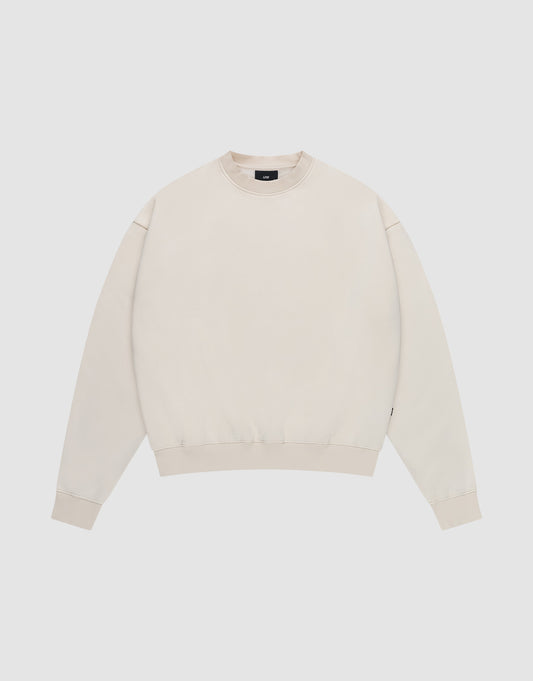 The LIVE FAST DIE YOUNG Basic Blank Sweater is a light beige, oversized crewneck with long sleeves, ribbed cuffs, hem, and collar, made from a soft cotton-polyester blend with a subtle flag label. Shown laid flat on a white background. | plain