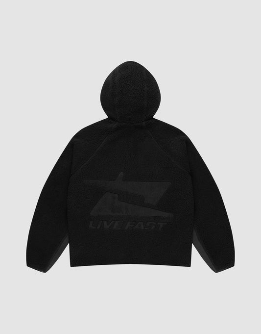 The Live Fast Teddy Jacket by LIVE FAST DIE YOUNG is shown from the back in black, with a large subtle stylized gun graphic and "LIVE FAST" near the hem. Raglan sleeves add comfort and style. Set against a light gray background.