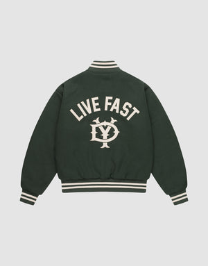 The LIVE FAST DIE YOUNG Live Fast College Jacket is dark green with a DY zipper, white striped cuffs and collar, and features large “LIVE FAST” text above an LV emblem on the back. Shown against a plain light background. | plain