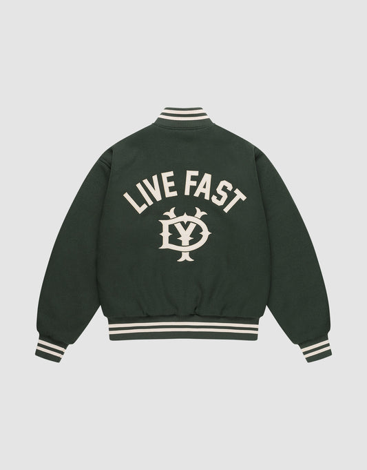 The LIVE FAST DIE YOUNG Live Fast College Jacket is dark green with a DY zipper, white striped cuffs and collar, and features large “LIVE FAST” text above an LV emblem on the back. Shown against a plain light background. | plain