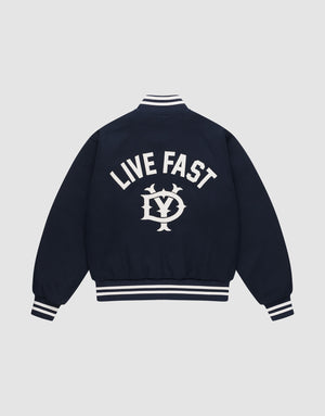 The Live Fast College Jacket by LIVE FAST DIE YOUNG is a navy varsity jacket with white striped cuffs, collar, and hem. The back features bold "LIVE FAST" Rückenstick text above an LV circular emblem. Regular fit for comfort and style. | plain