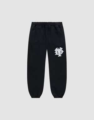 The DY Loose Jogger by LIVE FAST DIE YOUNG are black sweatpants with a loose fit, elastic waistband, cuffs, and a white abstract face graphic on the upper left thigh. Made from soft cotton, shown against a plain light gray background. | plain