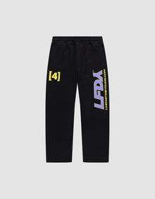 The LFDY Racing Wide Jogger by LIVE FAST DIE YOUNG features black sweatpants with a yellow “[4]” on the left thigh, bold white and purple “LFDY” on the right leg, an elastic waistband, wide fit, and quality cotton. Displayed on a plain light gray background. | plain