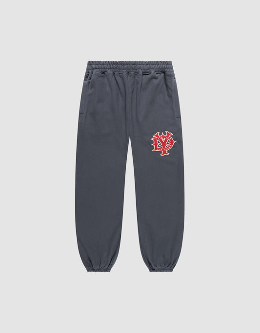 The DY Loose Jogger von LIVE FAST DIE YOUNG in Dunkelgrau ist eine locker geschnittene Sweatpants aus Baumwolle mit Elastikbund, Bündchen, Seitentaschen und rot-weißem Grafikprint am linken Oberschenkel vor hellem Hintergrund. | plain